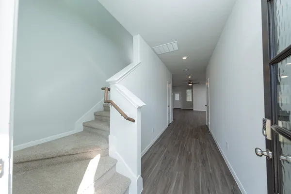 a view of a hallway with wooden floor and staircase