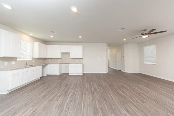 a large kitchen with wooden floors and white cabinets