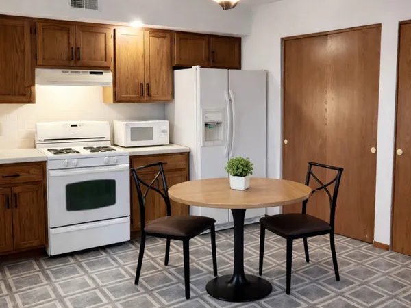 a kitchen with stainless steel appliances a stove a refrigerator a dining table and chairs