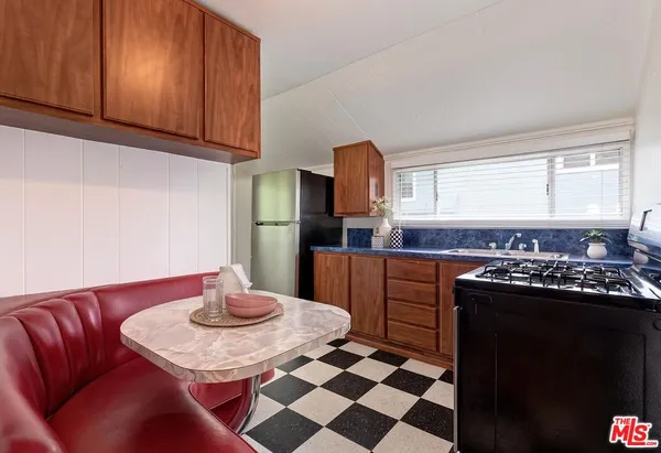 a kitchen with stainless steel appliances granite countertop a refrigerator a stove a sink dishwasher with a dining table and chair