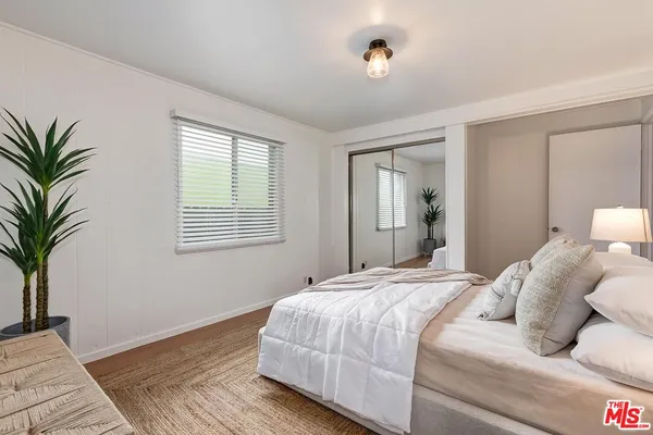 a bedroom with a large bed and a potted plant