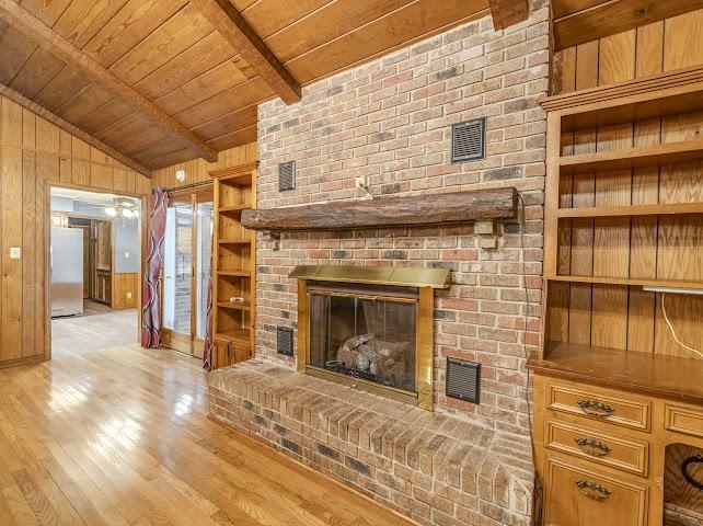 660 Hinton Road Counce, TN 38326 - Photo 11 of 40 Wood-finish flooring, exposed beam ceiling, brick fireplace with hearth, wood-paneled walls, and built-in shelving