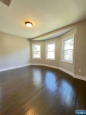 a view of an empty room with wooden floor and window