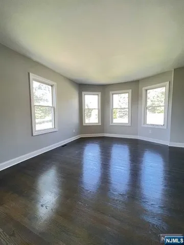 a view of an empty room with wooden floor and window