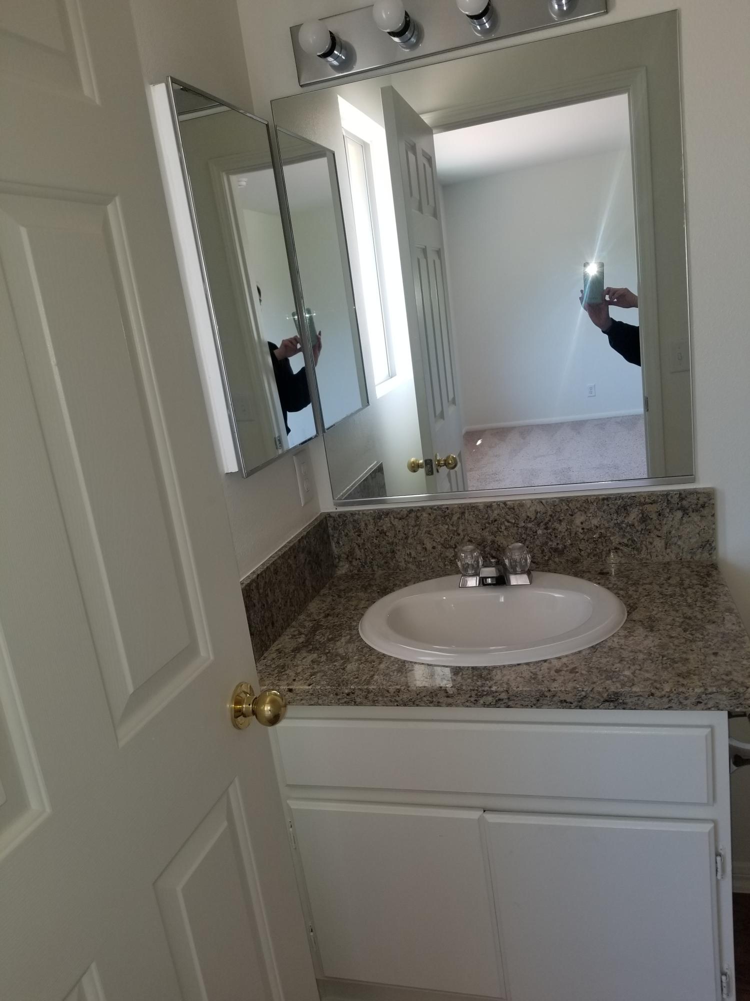 43487 30th Street West, Unit 2 Lancaster, CA 93536 - Photo 13 of 16 a bathroom with a granite countertop sink and a mirror