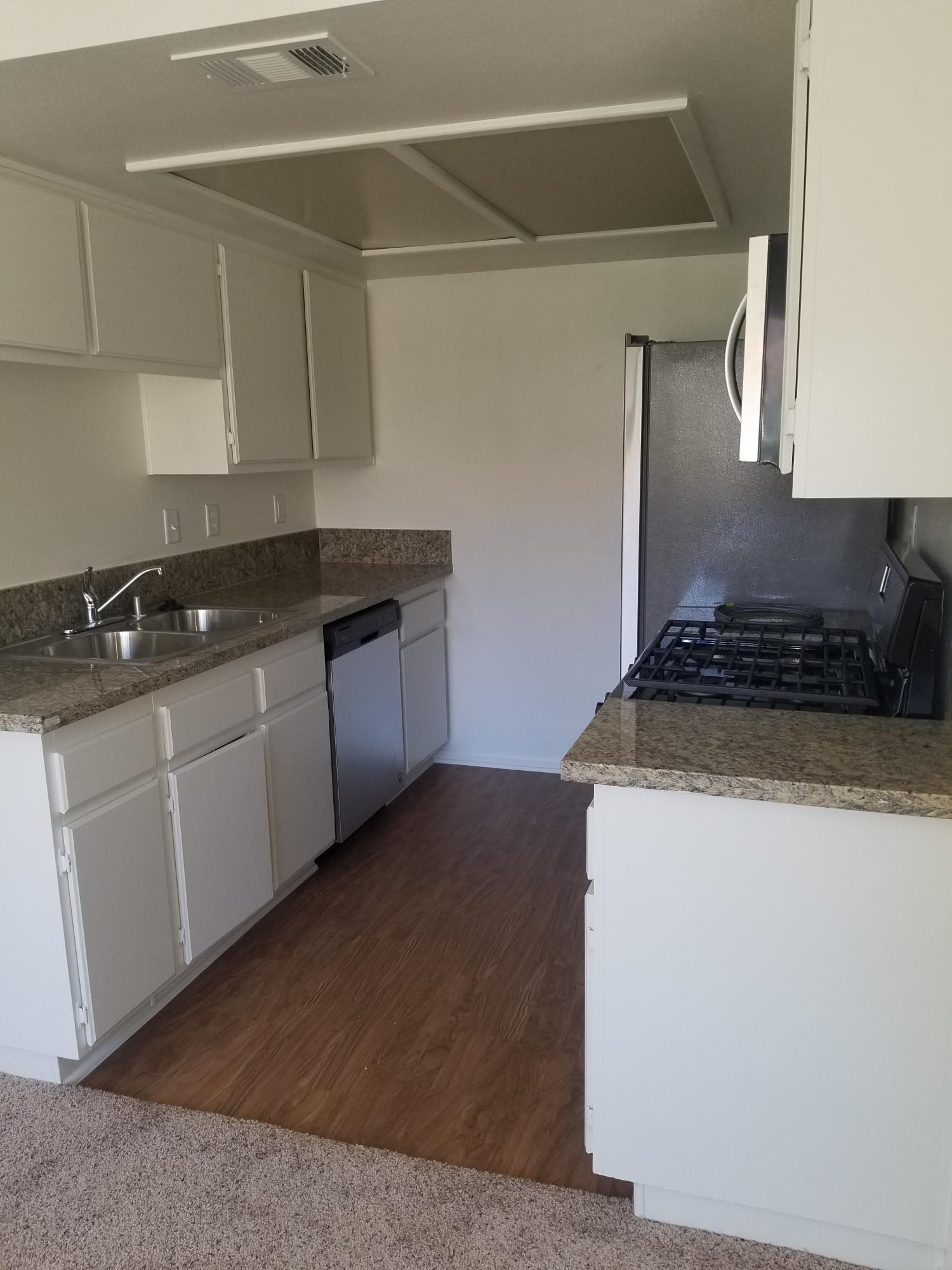 43487 30th Street West, Unit 2 Lancaster, CA 93536 - Photo 6 of 16 a kitchen with granite countertop a sink a stove and cabinets