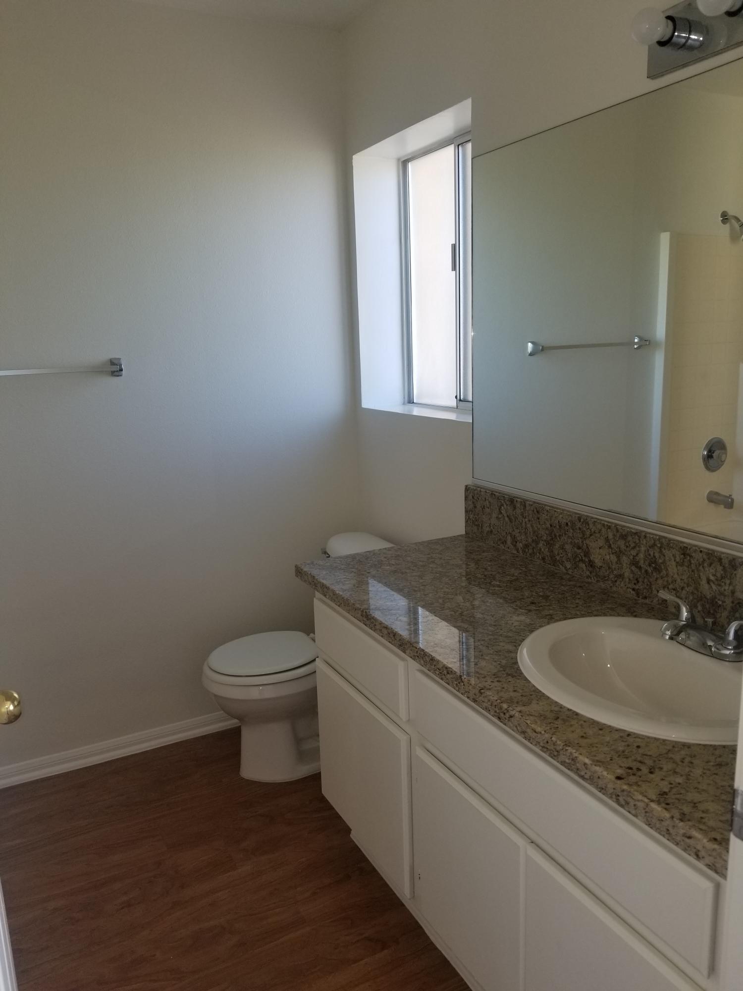 43487 30th Street West, Unit 2 Lancaster, CA 93536 - Photo 10 of 16 a bathroom with a granite countertop toilet a sink and mirror