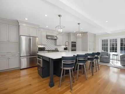 a kitchen with stainless steel appliances granite countertop a dining table chairs stove refrigerator and wooden floor