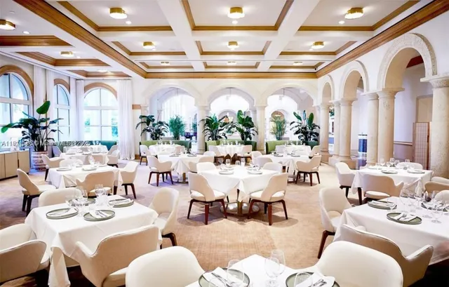 a very nice looking dining room with lots of white furniture and a large window