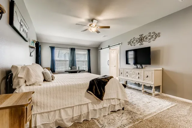 a bedroom with a bed television on desk and a window