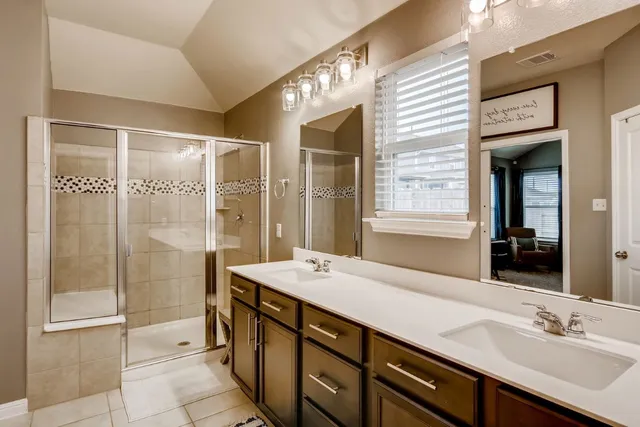 a bathroom with a double vanity sink a large mirror and shower