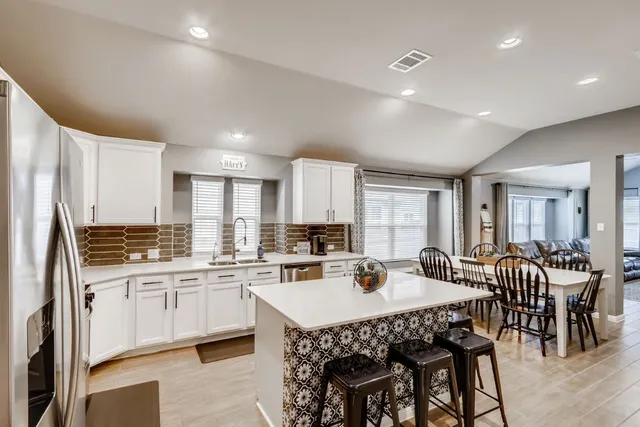 a kitchen with a dining table chairs and white cabinets