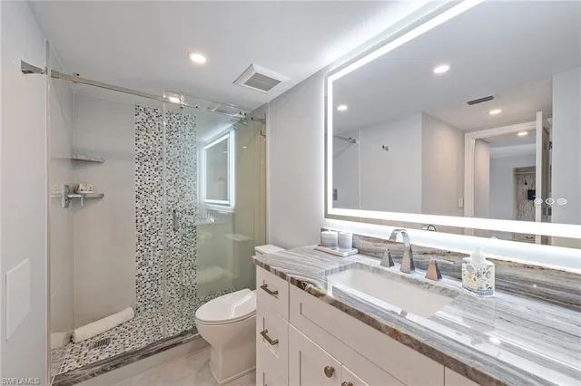 a bathroom with a granite countertop toilet sink and mirror
