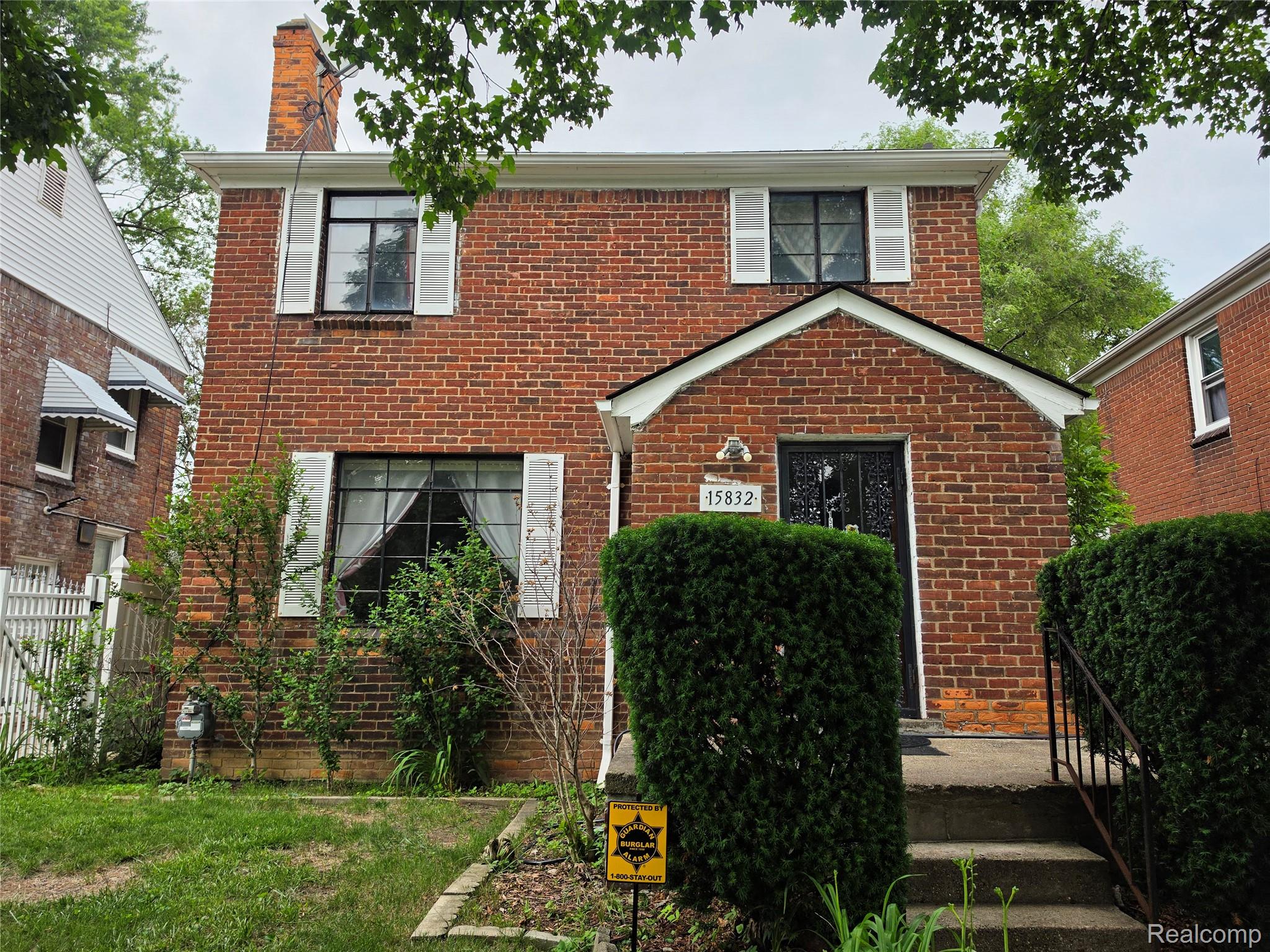 15832 Griggs Street Detroit, MI 48238 - Photo 2 of 24 Brick-clad residence featuring white window shutters, a front entry with an arched portico, and mature front landscaping