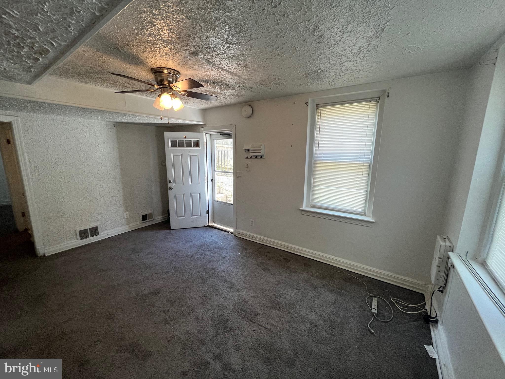 an empty room with a ceiling fan and window