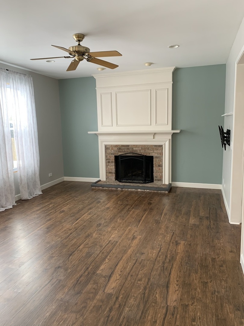 11860 Presley Circle Plainfield, IL 60585 - Photo 7 of 18 an empty room with wooden floor fireplace and windows