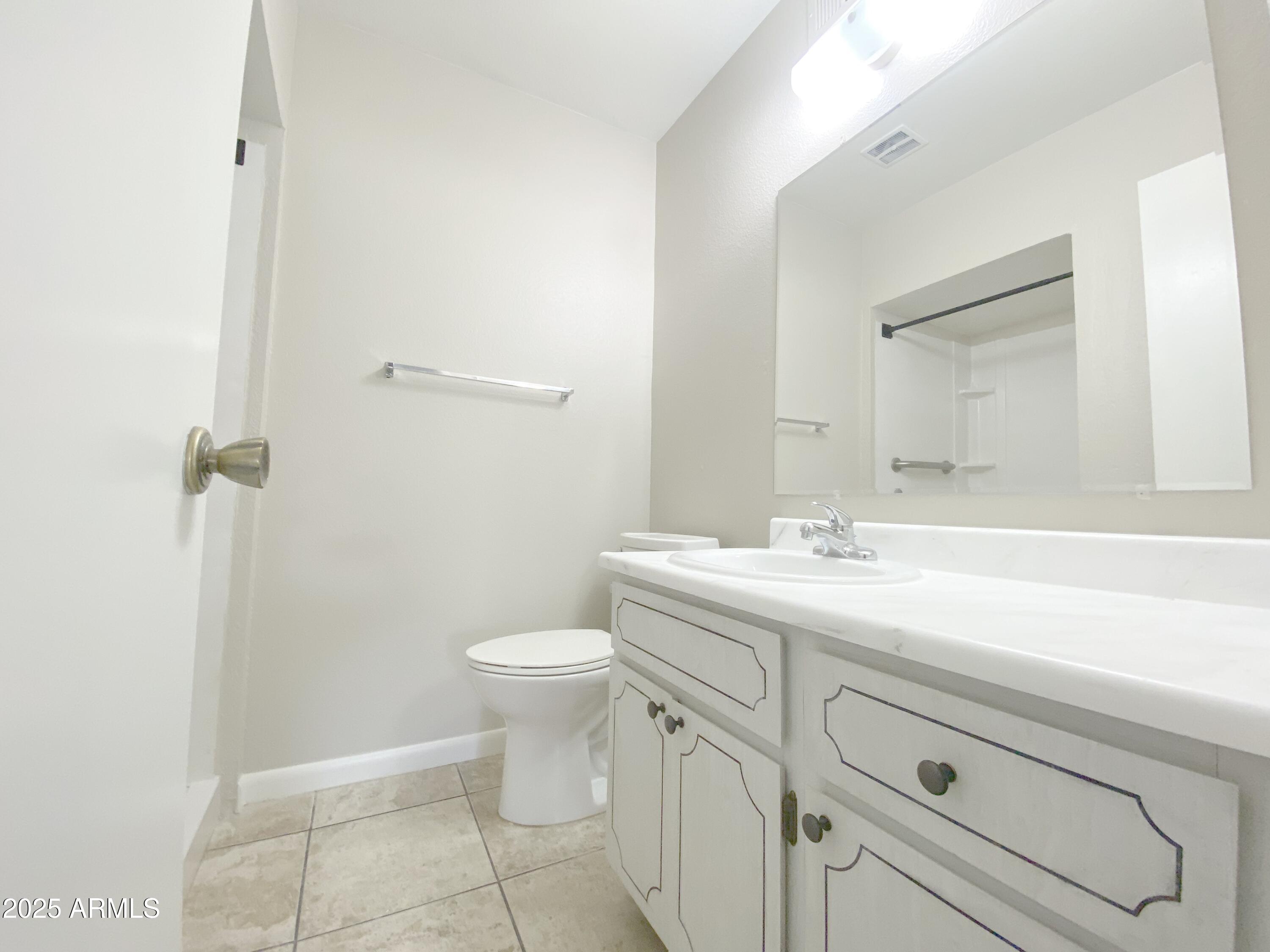 10417 North 95th Drive, Unit B Peoria, AZ 85345 - Photo 7 of 18 a bathroom with a toilet a sink a vanity and mirror