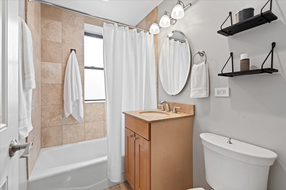 4144 North Sheridan Road, Unit 407 Chicago, IL 60613 - Photo 13 of 19 a bathroom with a granite countertop sink a toilet and shower