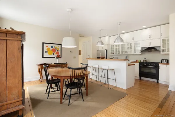 a kitchen with stainless steel appliances kitchen island granite countertop a table chairs sink and cabinets