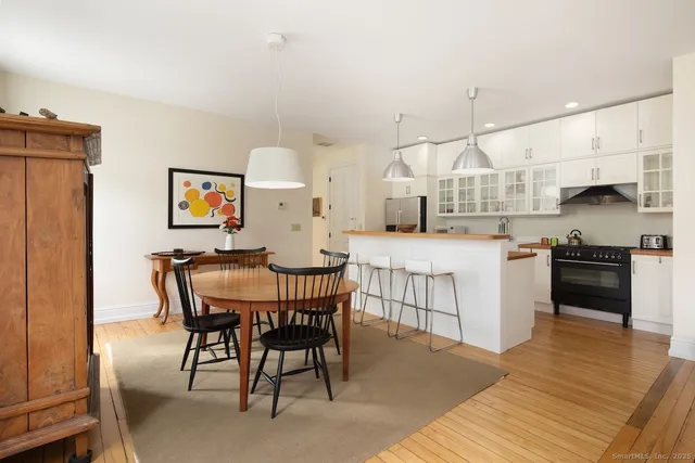 a kitchen with stainless steel appliances kitchen island granite countertop a table chairs sink and cabinets
