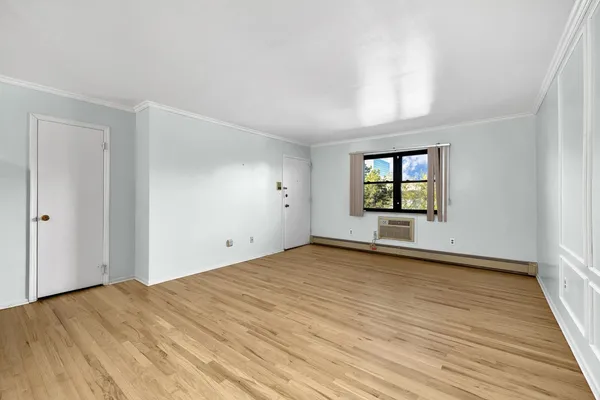 a view of an empty room with window and wooden floor