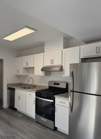 a kitchen with a refrigerator and white cabinets