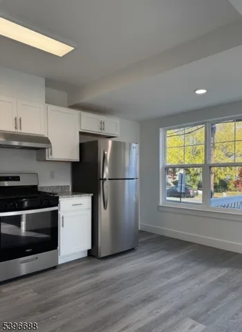 a kitchen with stainless steel appliances wooden floor and a window
