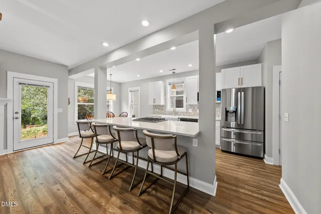 a kitchen with stainless steel appliances a dining table chairs and wooden floor
