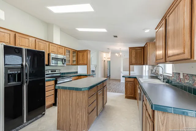 a kitchen with stainless steel appliances granite countertop a sink a stove and a refrigerator