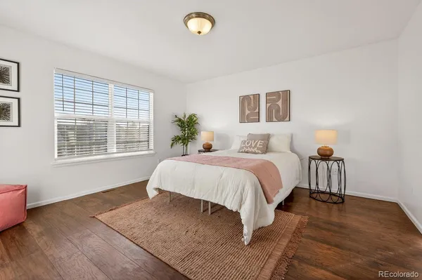 a spacious bedroom with a bed and wooden floor