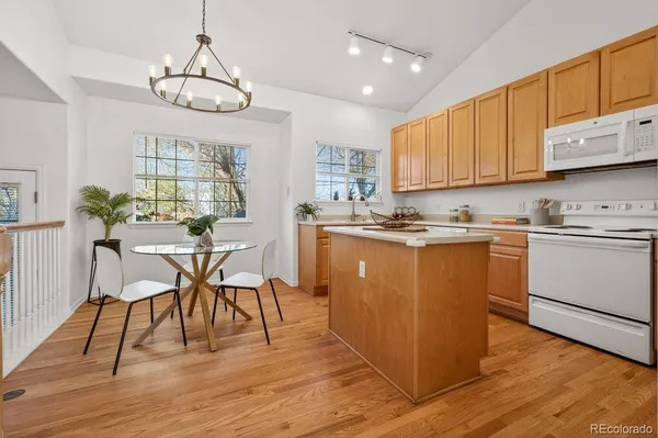 a kitchen with stainless steel appliances granite countertop a stove top oven a dining table and chairs with wooden floor