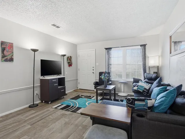 a living room with furniture a flat screen tv and a window