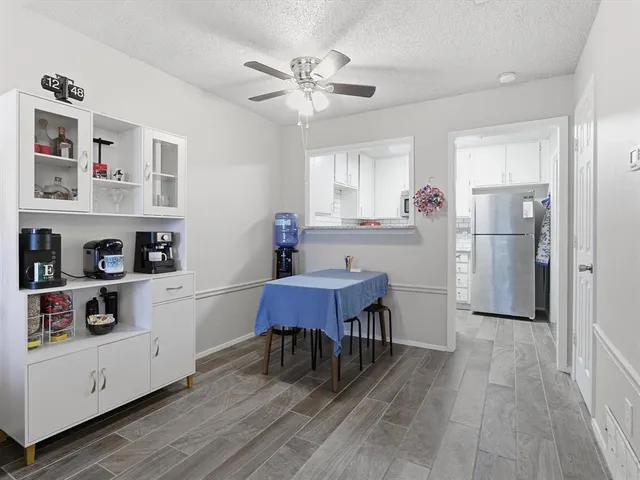 a kitchen with stainless steel appliances a dining table chairs refrigerator and cabinets