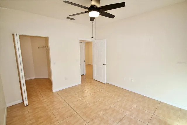 an empty room with closet and a chandelier fan