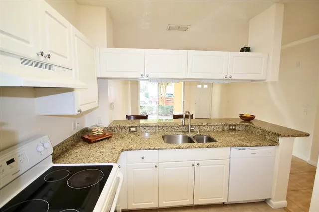 a kitchen with granite countertop a sink a stove and cabinets