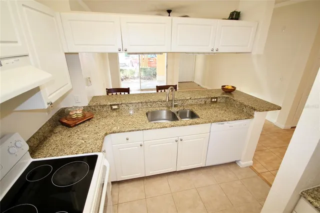 a kitchen with granite countertop a sink and a white cabinets