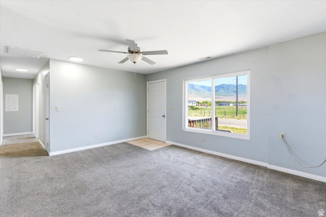 1613 Sunset Road Lake Point, UT 84074 - Photo 5 of 33 Carpeted interior with light gray walls, a ceiling fan, and a large window offering mountain scenery