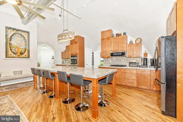 a dining hall with stainless steel appliances a dining table and chairs with wooden floor