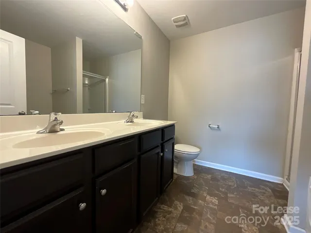 a bathroom with a double vanity sink toilet and a mirror