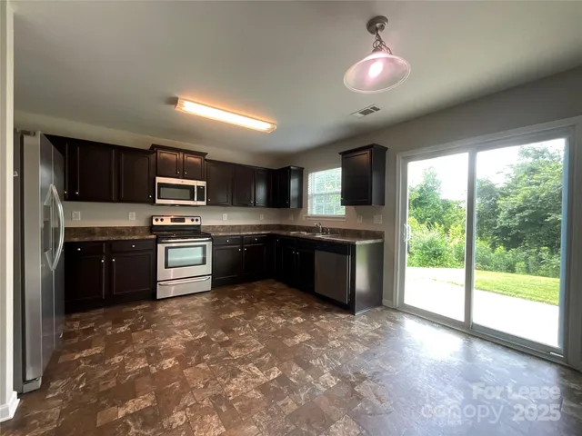 a kitchen with stainless steel appliances kitchen island granite countertop a stove sink and cabinets