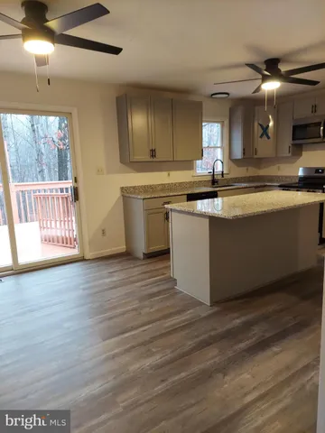a large kitchen with stainless steel appliances granite countertop a lot of counter space and wooden floors