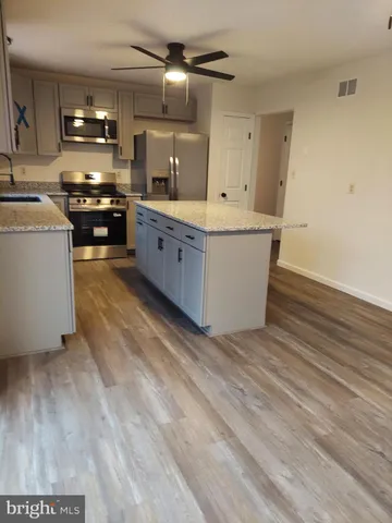 a large kitchen with kitchen island a sink dishwasher a stove and a refrigerator with wooden floor