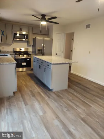 a large kitchen with stainless steel appliances a large counter top a stove and a sink