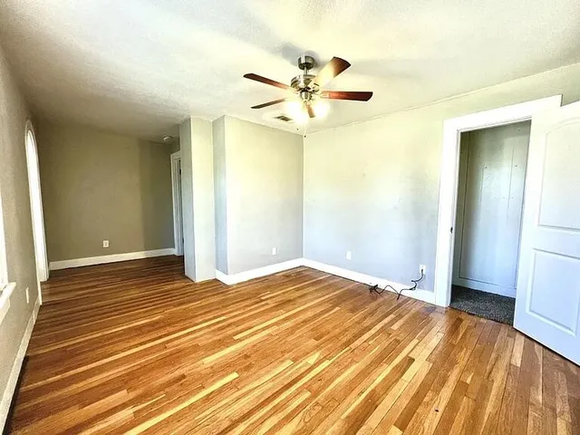 a view of a room with wooden floor and ceiling fan