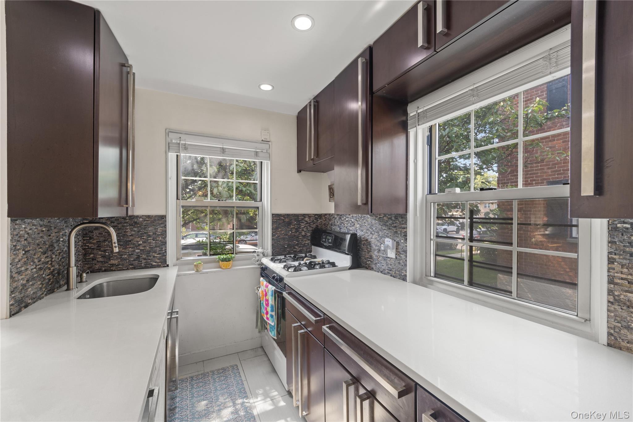 69-09 215th Street, Unit LOWER 1 Queens, NY 11364 - Photo 11 of 20 Kitchen with white gas range, light countertops, dark brown cabinetry, and recessed lighting