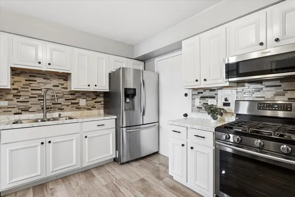 a kitchen with stainless steel appliances white cabinets sink and a refrigerator