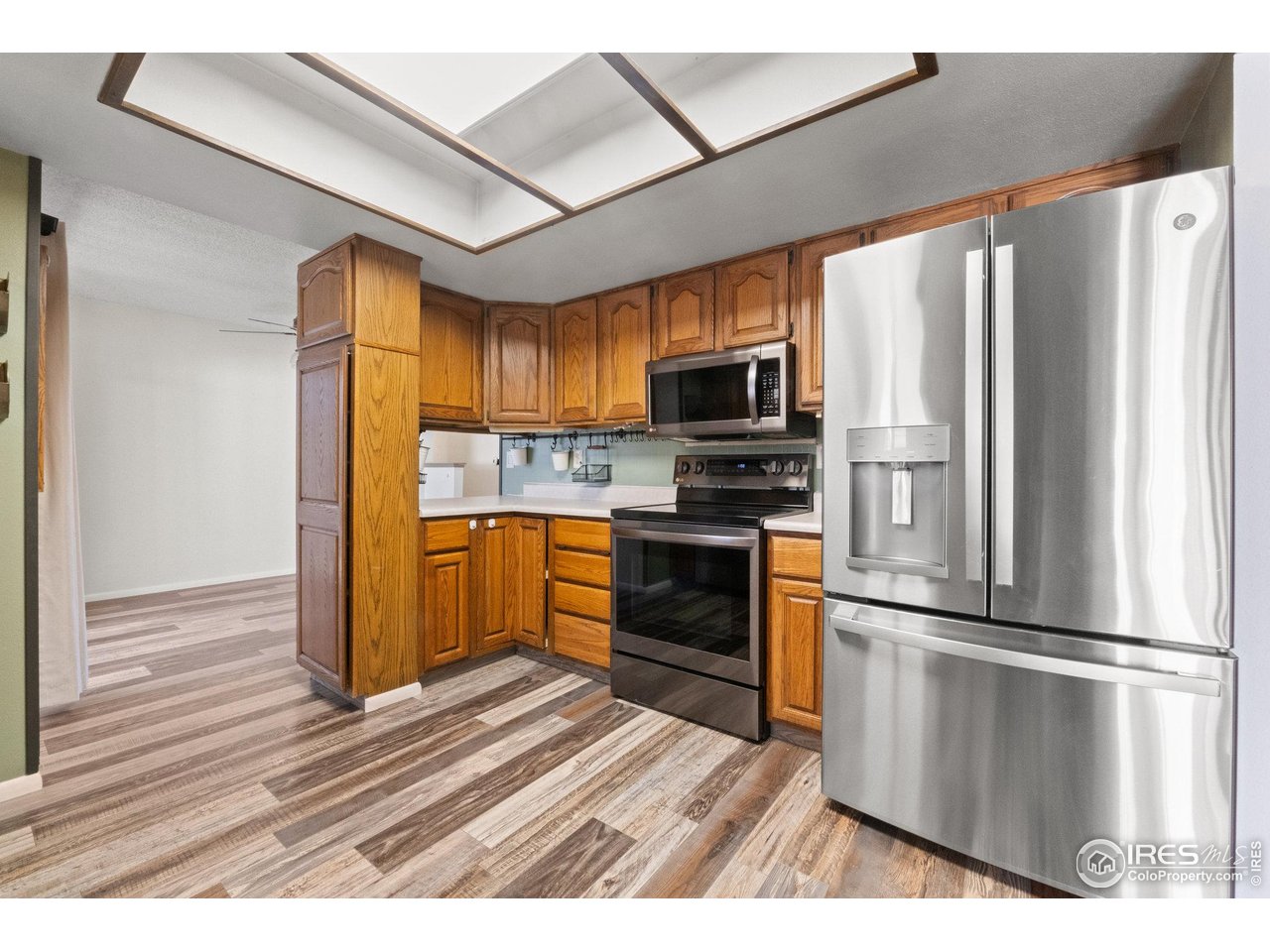 310 Apache Street Fort Morgan, CO 80701 - Photo 12 of 50 a kitchen with a refrigerator stainless steel appliances wooden floor and cabinets