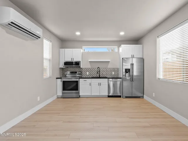 a large kitchen with cabinets wooden floor and stainless steel appliances