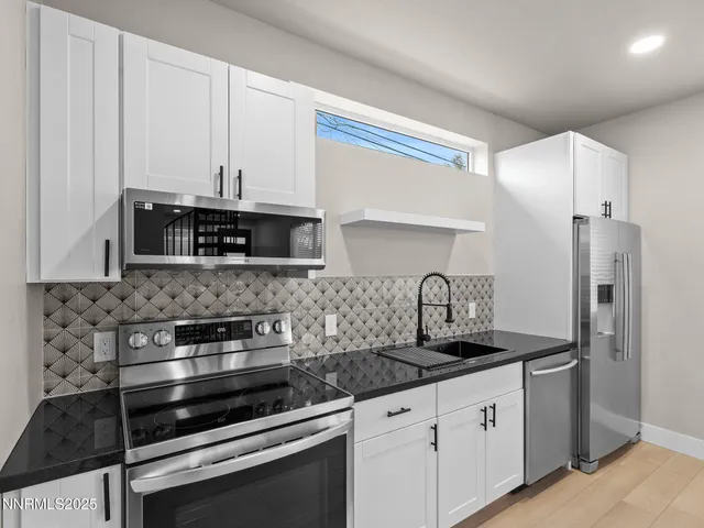 a kitchen with granite countertop white cabinets and stainless steel appliances