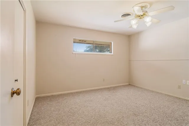 an empty room with a window and a fan